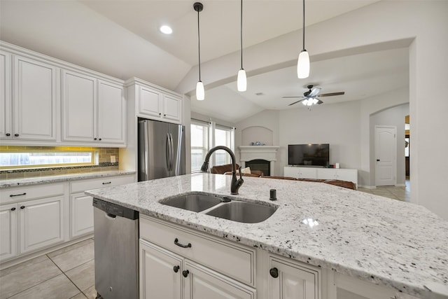 kitchen with lofted ceiling, light tile patterned flooring, a fireplace, a sink, and stainless steel appliances