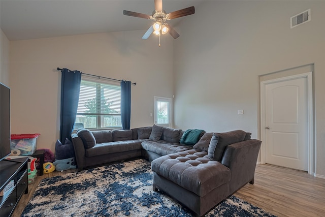 living room featuring high vaulted ceiling, a ceiling fan, light wood-style flooring, and visible vents