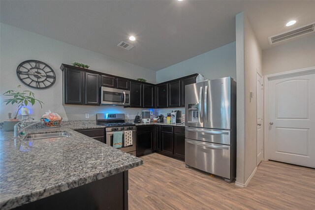 kitchen featuring visible vents, a sink, light stone counters, and stainless steel appliances