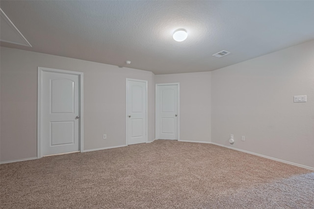 carpeted empty room with baseboards, a textured ceiling, and visible vents