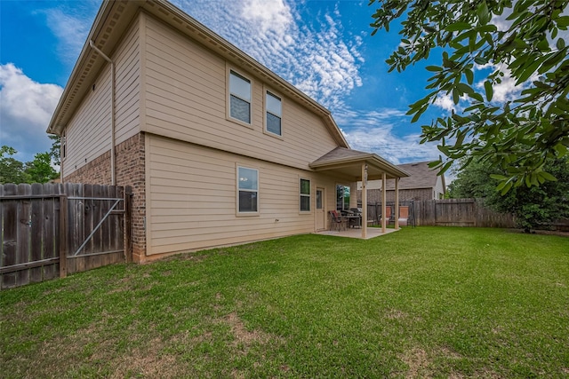 back of property with a fenced backyard, a yard, a patio area, and brick siding
