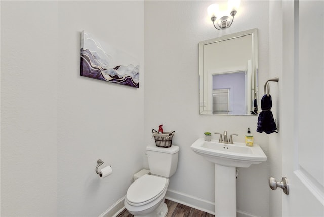 bathroom with toilet, baseboards, and wood finished floors