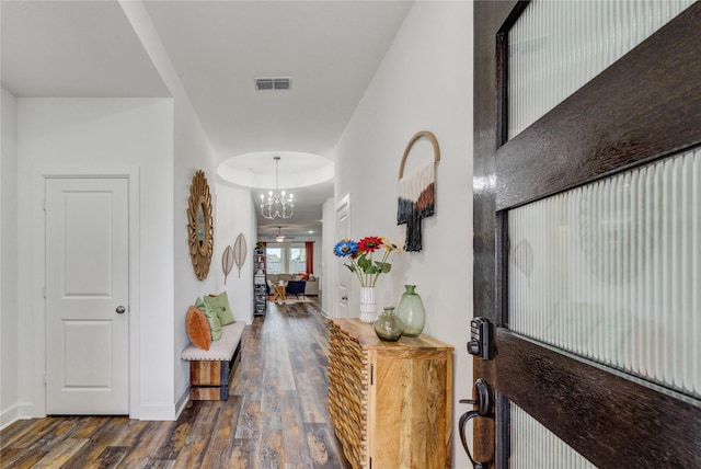 entryway with an inviting chandelier, baseboards, wood finished floors, and visible vents