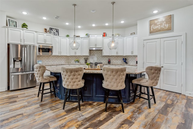 kitchen featuring white cabinetry, a kitchen island with sink, wood finished floors, and stainless steel appliances