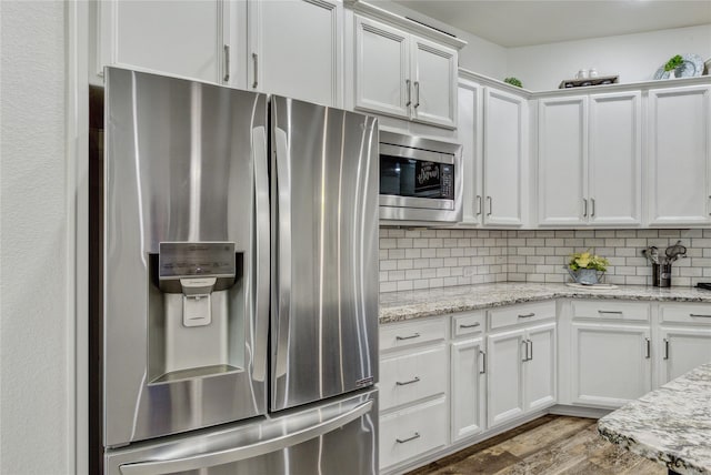 kitchen featuring white cabinetry, wood finished floors, tasteful backsplash, and stainless steel appliances