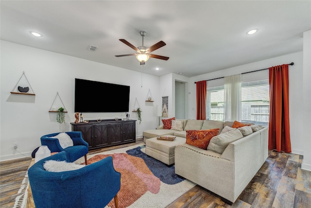 living area with baseboards, a ceiling fan, wood finished floors, and visible vents
