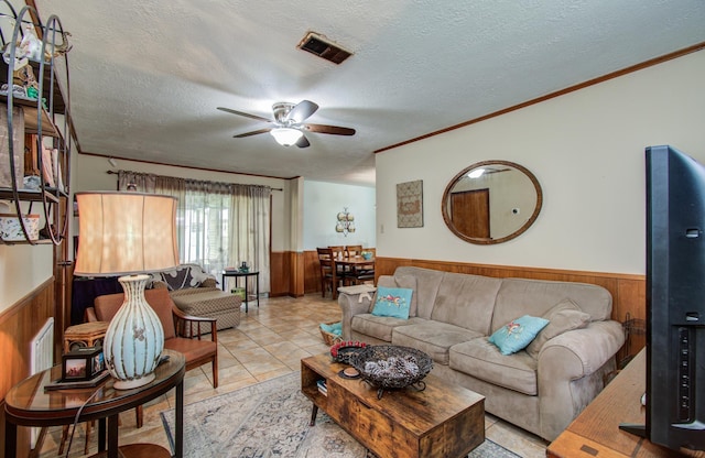 tiled living area with wooden walls, a ceiling fan, and a wainscoted wall