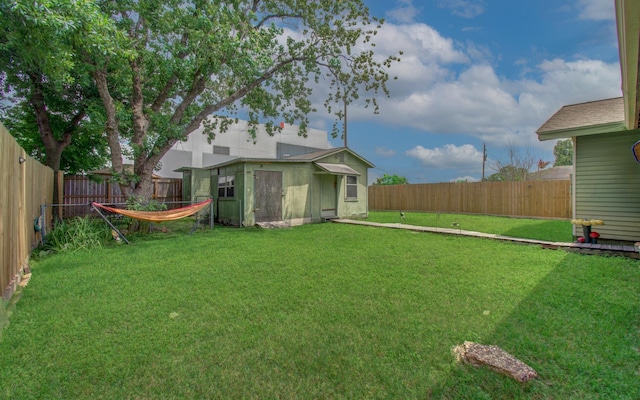 view of yard with an outbuilding, a fenced backyard, and a shed