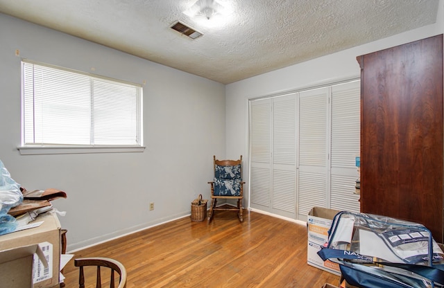 interior space featuring a textured ceiling, visible vents, baseboards, and light wood finished floors
