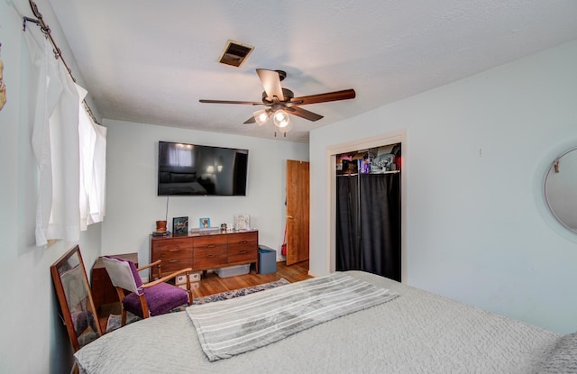 bedroom featuring ceiling fan, visible vents, wood finished floors, and a closet