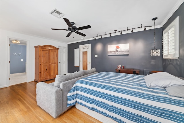 bedroom with visible vents, ornamental molding, ceiling fan, and wood finished floors