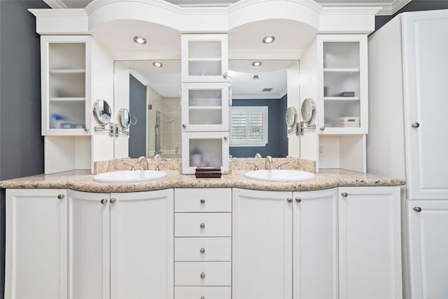 full bathroom with crown molding, a sink, double vanity, and a shower stall