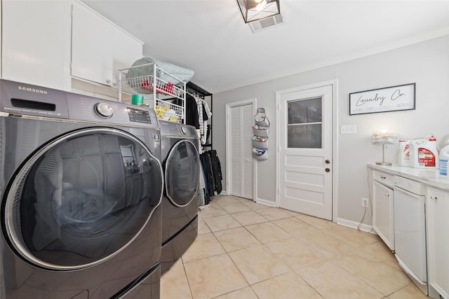 washroom featuring cabinet space, baseboards, light tile patterned floors, visible vents, and washing machine and dryer