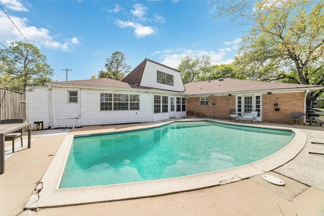 rear view of property featuring a patio, an outdoor pool, roof with shingles, and brick siding