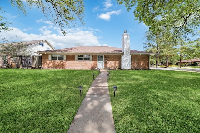 ranch-style home with a chimney, a front lawn, and brick siding