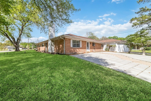 ranch-style home featuring a chimney, a front yard, driveway, and brick siding