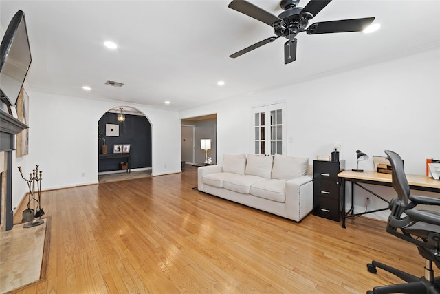 living area featuring ceiling fan, visible vents, ornamental molding, and light wood finished floors