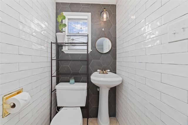 half bathroom with a sink, tile walls, and toilet
