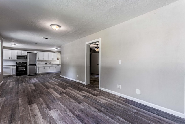 unfurnished living room featuring visible vents, baseboards, dark wood-type flooring, a textured ceiling, and a ceiling fan