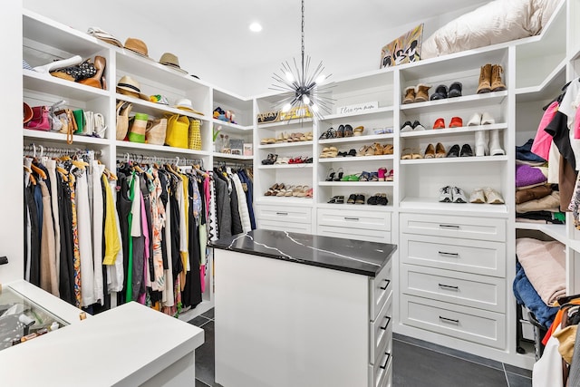 walk in closet featuring dark tile patterned floors and a notable chandelier