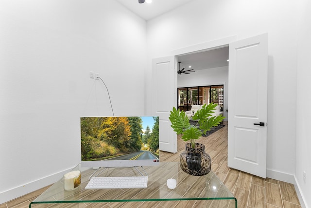 interior space featuring a ceiling fan, baseboards, and wood tiled floor