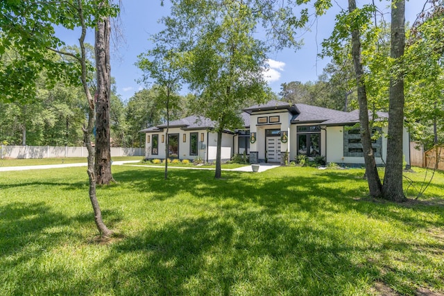 back of property featuring a lawn, stucco siding, and fence