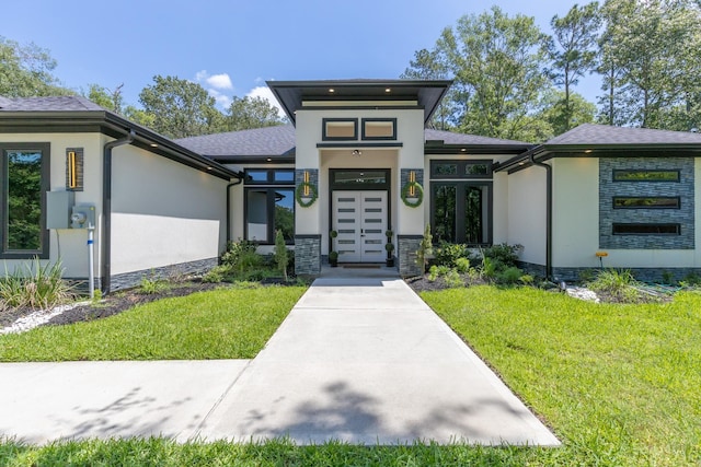 view of front of home featuring french doors, stucco siding, stone siding, and a front yard