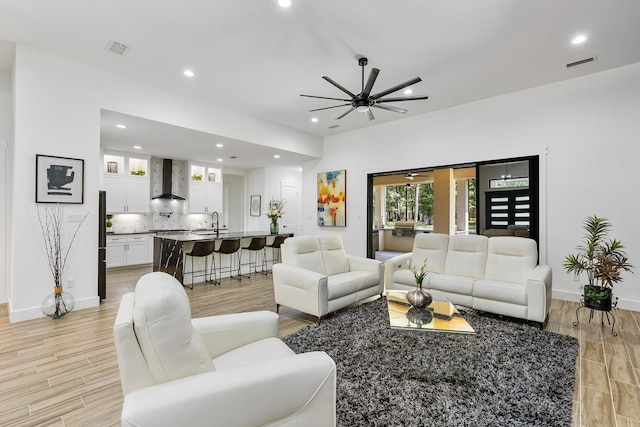 living room with light wood-style floors, a ceiling fan, baseboards, recessed lighting, and visible vents