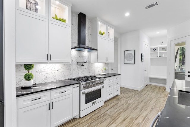 kitchen with wall chimney range hood, light wood-style flooring, baseboards, visible vents, and range with gas cooktop