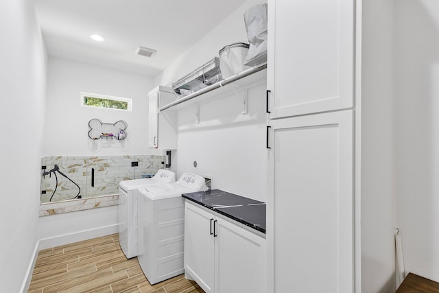 washroom featuring cabinet space, visible vents, washing machine and dryer, and light wood-style floors