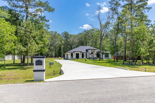 view of front of property featuring fence, driveway, and a front yard