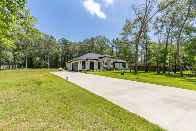 view of front of home with fence, an attached garage, concrete driveway, and a front lawn