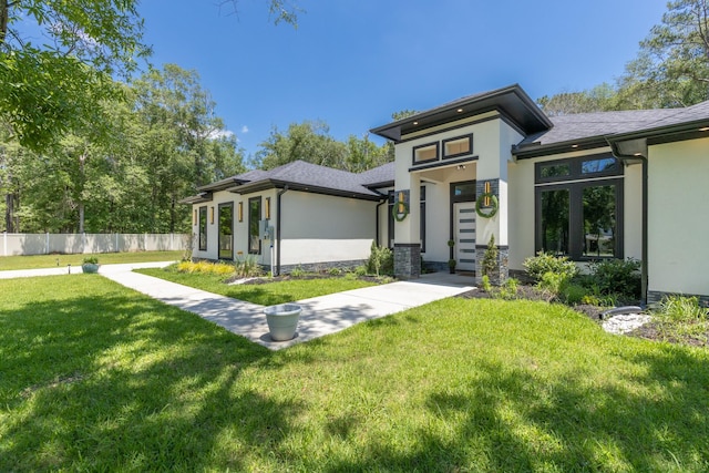 view of front of house with stucco siding, a front yard, and fence