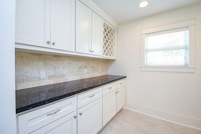 1406 Foxwood Rd, Houston, TX 77008 - kitchen with light tile patterned floors, dark stone counters, decorative backsplash, and white cabinetry