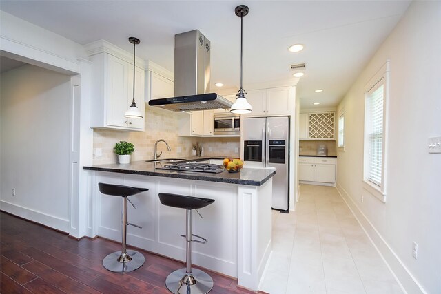 1406 Foxwood Rd, Houston, TX 77008 - kitchen featuring a peninsula, tasteful backsplash, island exhaust hood, a sink, and stainless steel appliances