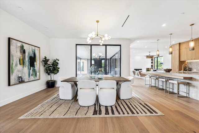 dining room featuring light wood-type flooring, recessed lighting, baseboards, and a notable chandelier