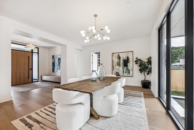 dining area with a chandelier, a wealth of natural light, and light wood-type flooring