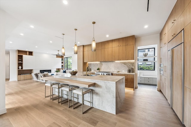 kitchen with modern cabinets, tasteful backsplash, a sink, light wood-style floors, and recessed lighting