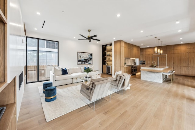 living area featuring recessed lighting, light wood-style flooring, ceiling fan, and wine cooler