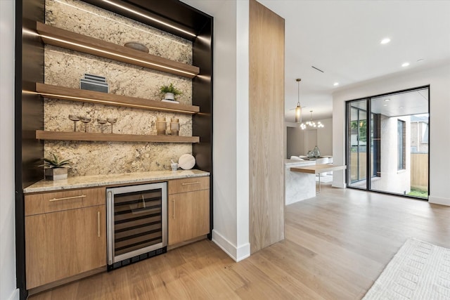 bar featuring beverage cooler, light wood-style flooring, recessed lighting, tasteful backsplash, and a bar
