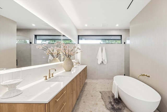 bathroom featuring a sink, a walk in shower, double vanity, and a freestanding bath