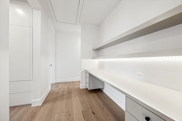 unfurnished office with light wood-style floors, attic access, and baseboards