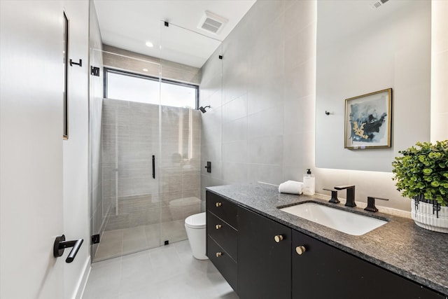 bathroom featuring tile walls, tile patterned flooring, a stall shower, vanity, and toilet