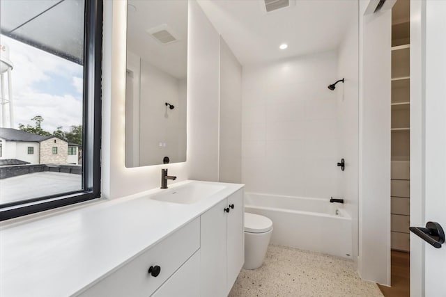 full bath featuring vanity, visible vents, toilet, washtub / shower combination, and speckled floor