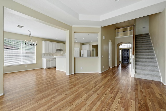 11030 Sprucedale Ct, Houston, TX 77070 - unfurnished living room featuring arched walkways, a chandelier, light wood-style floors, and baseboards