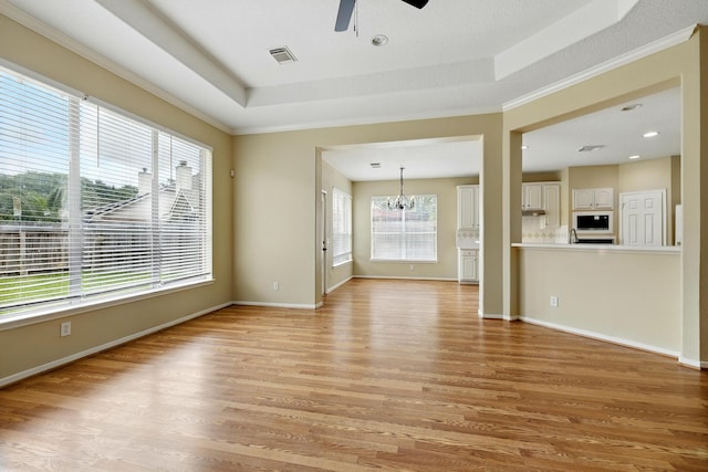 11030 Sprucedale Ct, Houston, TX 77070 - unfurnished living room with light wood-style flooring, a tray ceiling, a ceiling fan, a chandelier, and ornamental molding