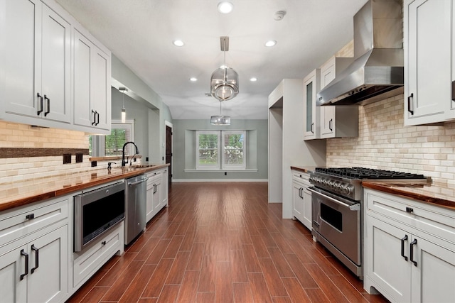 230009 Kama Dr, Porter, TX 77365 - kitchen featuring wall chimney range hood, appliances with stainless steel finishes, a sink, baseboards, and wood counters