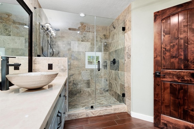 230009 Kama Dr, Porter, TX 77365 - full bathroom featuring wood tiled floor, a textured ceiling, a stall shower, baseboards, and vanity