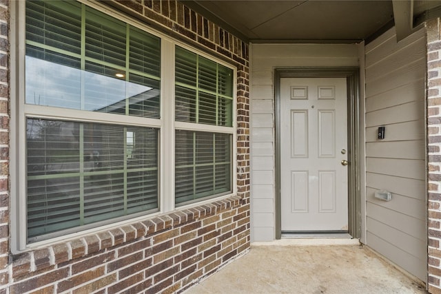 property entrance featuring brick siding and covered porch