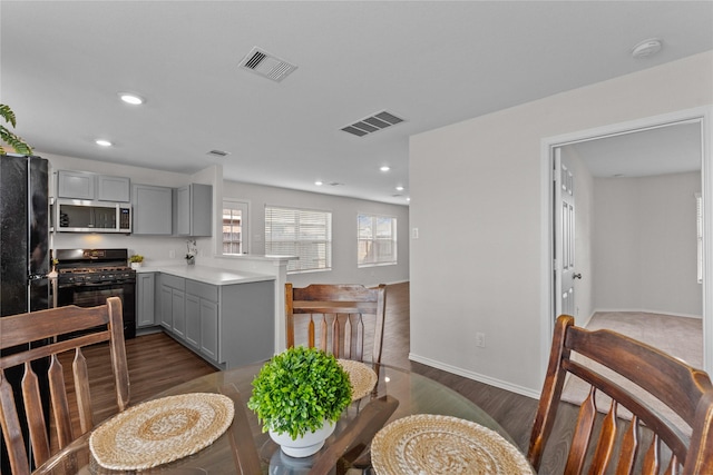 kitchen with gray cabinets, black appliances, a peninsula, and visible vents